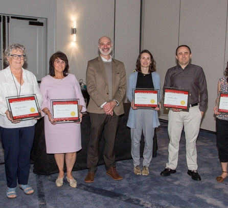 Agustin Rayo stands with five winners of the 2023 Infinite Mile Awards, each of them holding up their plaque for the camera