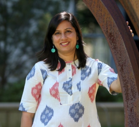 Sana Aiyar headshot with blurred background of green luscious trees