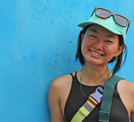 Headshot of Sophia Chen against a bright blue wall by D-Lab