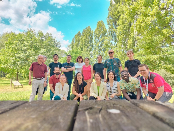 Yijun Yang and 15 other people in a field filled with green trees and the foreground was a wooden table